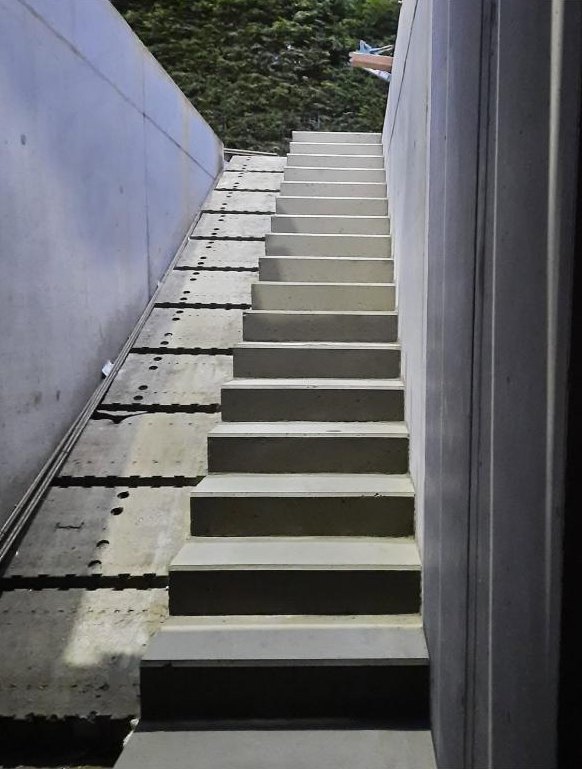 Buitentrap in beton tussen twee betonwanden, bij valavond