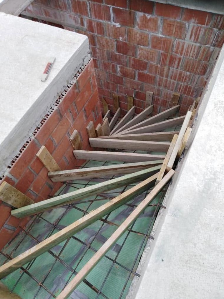 Bekisting met wapening van een kwartdraaiende trap tussen bakstenen muren